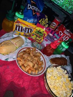 a table topped with lots of food next to sodas and candy bar wrappers