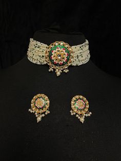 Indian Ladies' Pearl Choker & Earrings of Kundan & Green Meenakari Work Contemporary Indian bridal set with multilayered pearl strands choker and studded earrings. This bridal choker jewelry set is accented with green meenakari pendant and Kundan gemstones making it one of a kind. Gold plated choker with cluster pearls drops adorns this bridal necklace.  This modern choker is sure to make you feel like a million bucks with its elaborating multiple pearl strands in a handcrafted design. This shor Luxury Meenakari Pearl Earrings For Wedding, Green Meenakari Choker For Festivals, Festive Green Meenakari Choker, Green Meenakari Temple Jewelry Choker, White Meenakari Temple Jewelry Choker, White Meenakari Choker For Festivals, Meenakari Choker Jewelry Sets For Festivals, Round Meenakari Choker For Celebrations, Green Cutdana Choker Jewelry