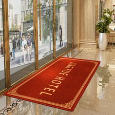 a hotel entrance mat on the floor in front of glass doors with people walking by