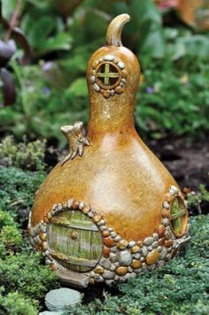 a small brown vase sitting on top of a green patch of grass next to plants