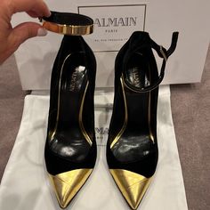 Pre Owned Authentic Balmain Paris Black And Gold Velvet Pumps With Gold Metal Ankle Closure Size 37 Made In Italy Comes With Original Box And Dust Bag Very Minor Scuff Front Of Right Side Adjustable Ankle Closure Luxury Heels With Contrasting Heel Counter, Court Shoes With Contrasting Heel Counter For Party, Luxury Ankle Strap Heels For Office, Designer Heels With Contrasting Heel Counter And Pointed Toe, Designer Heels With Contrasting Heel And Pointed Toe, Luxury Court Shoes With Wrapped Heel And Round Toe, Luxury Court Shoes With Wrapped Heel, Luxury Evening Court Shoes With Reinforced Heel, Evening Closed Toe Heels With Contrasting Heel Counter