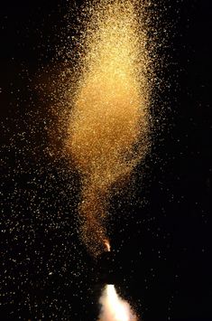 a large amount of yellow powder is flying in the air with it's reflection