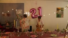 two people standing in front of a table set for a dinner party with pink plates and silverware