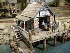 a miniature model of a small store on a wooden dock with people standing outside it