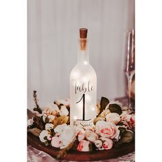 a wine bottle sitting on top of a table with flowers and candles in front of it