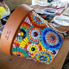 a wooden table topped with lots of plates and bowls covered in colorful mosaic tiles on top of it