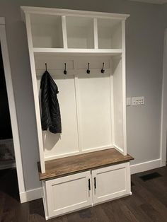 a coat rack with two coats hanging from it's hooks and some cupboards