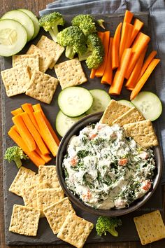 a platter with crackers, cucumbers, carrots and broccoli