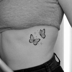 a black and white photo of two butterflies on the side of a woman's stomach