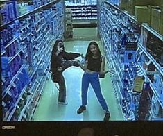 two women are standing in the aisle of a store and one is pointing at something