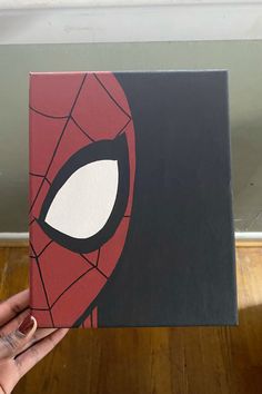 a hand holding up a book with a spiderman face on it