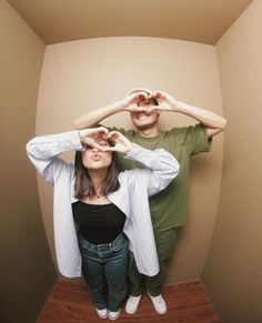 a man and woman standing next to each other with their hands on their foreheads