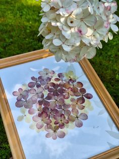 a vase filled with white flowers sitting on top of a wooden table next to a painting