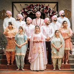 a group of people standing next to each other in front of a building with flowers