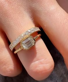 a close up of a person's hand with an engagement ring on their finger