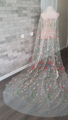 a wedding veil with flowers on it sitting in front of a door and brick wall