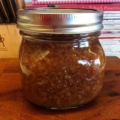 a glass jar filled with food sitting on top of a wooden table next to a stack of books