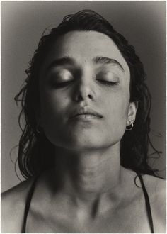 a black and white photo of a woman with her eyes closed, wearing a bra