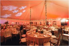 the inside of a tent with tables and chairs set up for a formal dinner party