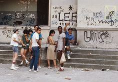 a group of people standing in front of a building with graffiti on the walls and steps