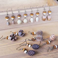 several pairs of pine cone earrings are displayed on a wooden table next to ear hooks