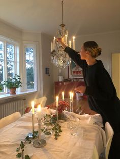 a woman lighting candles on a dining room table