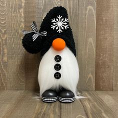 a black and white snowman with an orange nose on top of a wooden surface