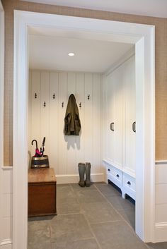 an entry way with white cabinets and coat hooks on the wall, along with a bench