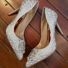 a pair of silver high heeled shoes sitting on top of a wooden floor