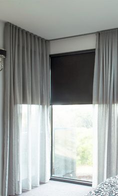 a bed sitting next to a window covered in curtains