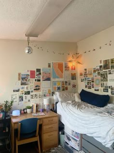 a dorm room with a bed, desk and pictures on the wall above it's headboard