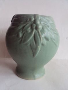 a green vase sitting on top of a white table