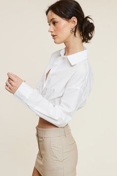 This White Giselle Shirt is the perfect addition to your wardrobe. With a cinched waist and overlap stitching details, it creates a lengthened torso effect for a unique and flattering look. The perfect cropped fit makes it a great standalone top. Elevate your style with this one-of-a-kind button-up. Fabric & fit: 80% nylon 20% cotton Model is wearing size Small. Chic Cropped Office Shirt, Spring Workwear Tops With Cropped Hem, Elegant Button-up Cropped Shirt For Work, Classic Cropped Shirt For Office, Chic Cropped Shirt For Office, Trendy Cropped Shirt For Spring, Trendy Cropped Tops For Office, Elegant Cropped Shirt, Elegant Button-up Cropped Shirt For Spring