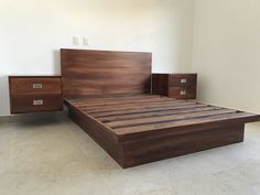 a bed with two nightstands and a wooden headboard in a room that has white tiles on the floor