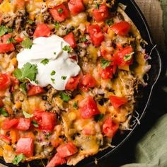 a skillet filled with mexican food and sour cream