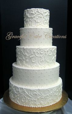 a three tiered white wedding cake sitting on top of a gold plated platter