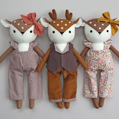 three stuffed animals are lined up on the wall, one is wearing overalls and the other has a bow