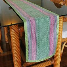 a table with a green and pink runner on top of it next to a chair