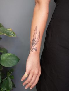 a woman's arm with a tattoo on it and a plant in the background