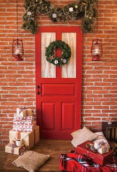 a red door with wreaths and presents in front of it on a wooden floor