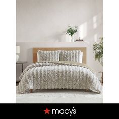 a bed in a room with white walls and plants on the headboard, along with an advertisement for macy's