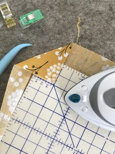 the scissors are laying on top of the cutting mat next to the sewing machine and thread spools