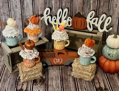 cupcakes and pumpkins are on display in front of a sign that says hello fall