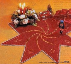 a crocheted red star with candles on it and some flowers in the center