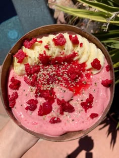 a person holding up a bowl of food with bananas and raspberries on it