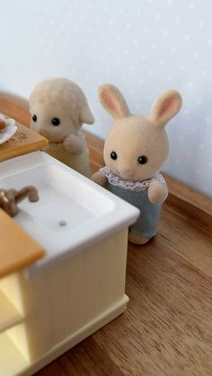 two small stuffed animals sitting next to a sink