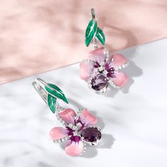 Creating a refreshing appeal with its delicate floral design, this pair of enamel earrings is a masterpiece in itself. These lovely earrings embody the youth of flowers and the freshness of spring. Pink and purple flowers and green enamel leaves are adorned with purple oval-cut stones and white round-cut stones in polished sterling silver. Pair it up with a pretty floral print dress and you're good to go for a happening day out or at a party.Carat Weight: 0.63 ctStone Shape: RoundStone Size: 1,1 Seed Bead Flowers, Jewelry Illustration, Pink And Purple Flowers, Sterling Silver Drop Earrings, Enamel Earrings, Spring Flower, Green Enamel, Lovely Earrings, Silver Drop Earrings