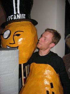 a man standing next to a giant pumpkin wearing a top hat