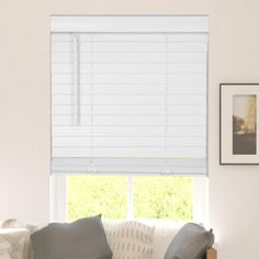 a living room with a couch and window covered in white roman blind shades on the windowsill