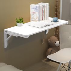 a white desk with books and a teddy bear in the corner next to it,